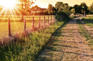 Paysage de campagne française au coucher du soleil, chemin ar clôture dans les champs à Vaas, Sarthe - France