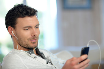 Young man using mobile phone with handsfree headset