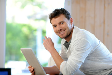 Handsome man relaxing at home with digital tablet