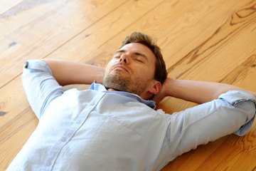 Young man relaxing on wooden floor in apartment
