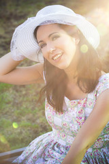 Fototapeta premium Happy woman in the park with hat under sunburst
