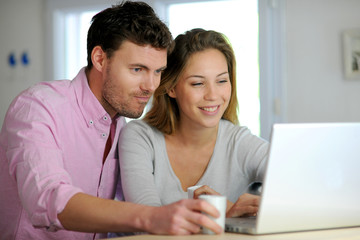 Happy couple websurfing on laptop computer at home