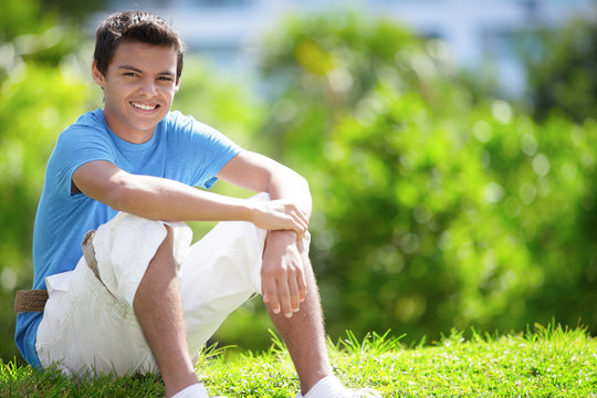 Teenager sitting on a hill in the park