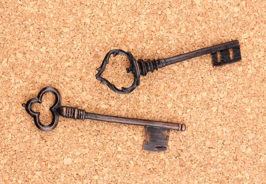 Two antique keys on cork background