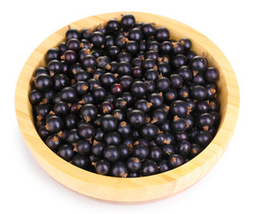 Black currant in wooden bowl isolated on white