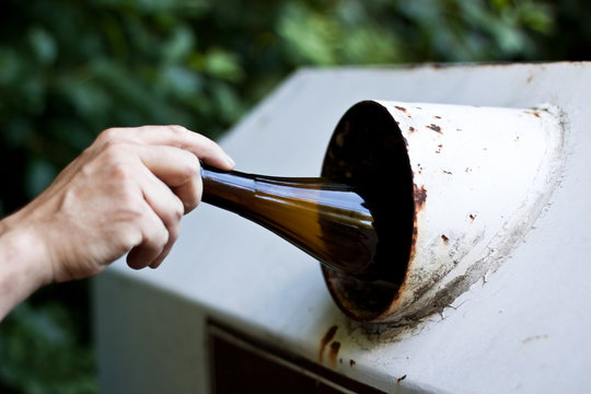 Entsorgung einer braunen Flasche in den Glascontainer
