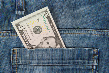 Macro shot of trendy jeans with american 5 dollar bill