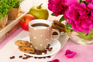 cup of coffee, cookies, apples and flowers on table in cafe