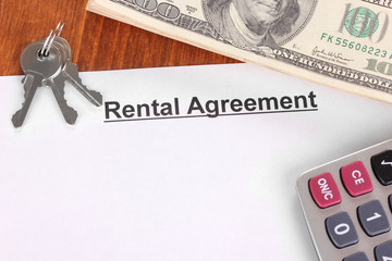 Rental agreement with dollars on wooden background close-up