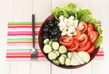 tasty Greek salad on white wooden background