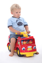 little boy sitting on a toy car