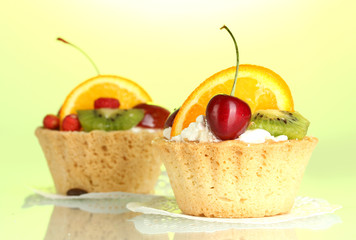 sweet cakes with fruits on green background