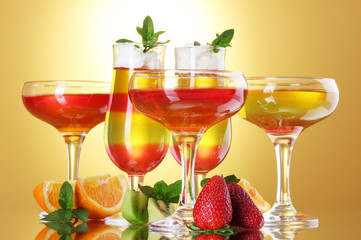 fruit jelly in glasses and fruits on yellow background