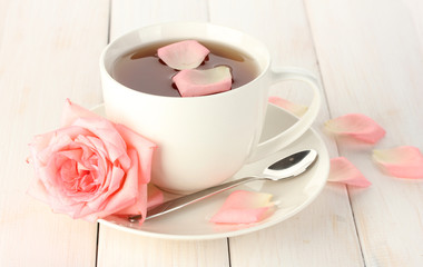 cup of tea with rose on white wooden table