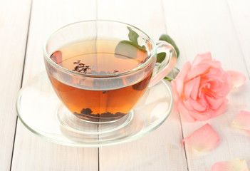 cup of tea with rose on white wooden table