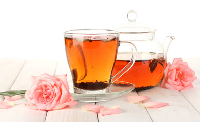 teapot and cup of tea with roses on white wooden table