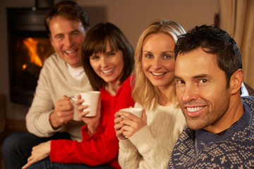 Group Of Middle Aged Couples Sitting On Sofa With Hot Drinks Tal