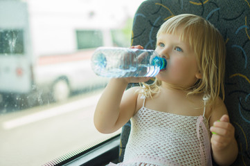 Baby in white dress drink water ride bus