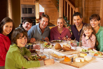 Two Familes Enjoying Meal In Alpine Chalet Together