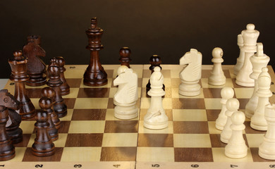 Chess board with chess pieces on brown background