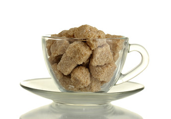 Lump brown cane sugar cubes in glass cup isolated on white