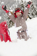 Young Girl Playing In Snow With Sledge On Ski Holiday In Mountai