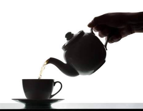 Teapot pouring tea into a cup. Silhouette
