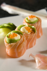 Three salmon sushi rolls with chopsticks