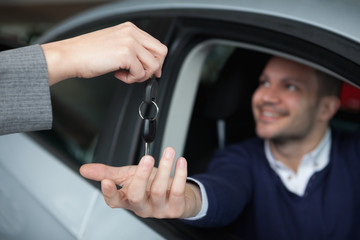 Man receiving car keys while sitting in his car