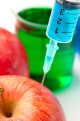 Close up of a syringe injecting liquid into an apple