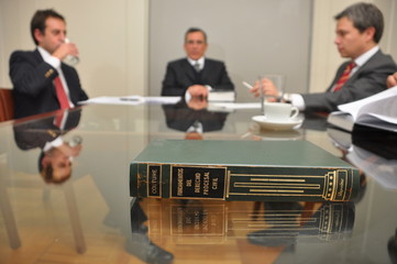 avvocati durante una riunione seduti ad un tavolo di vetro con un testo di legge