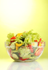 fresh vegetable salad in transparent bowl on green background