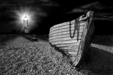 Foto auf Acrylglas Leuchtturm Boot am Strand, beleuchtet vom Licht des Leuchtturms