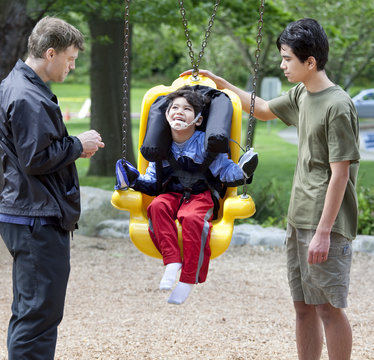 Disabled little boy swinging on special needs swing