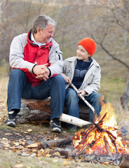 Grandfather and grandson around a campfire