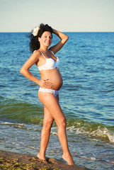 Smiling pregnant woman at the beach