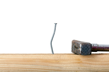 Crooked nail in the wooden board with a hammer