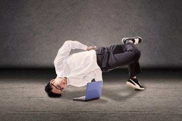 Businessman breakdancing with laptop