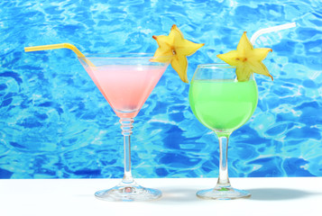 Glasses of cocktails on table on blue sea background