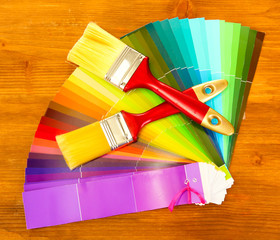 paint brushes and bright palette of colors on wooden background