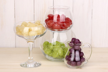 Color candies in glasses on wooden background