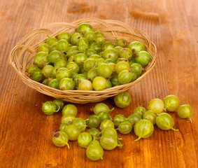 Green gooseberry in basket on wooden background