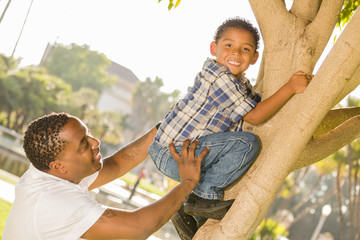 Happy Mixed Race Father Helping Son Climb a Tree