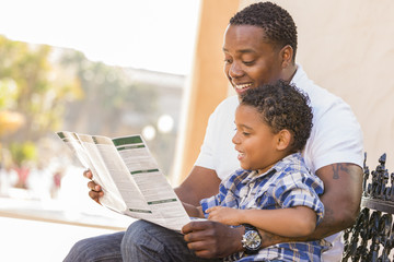 Mixed Race Father and Son Reading Park Brochure Outside