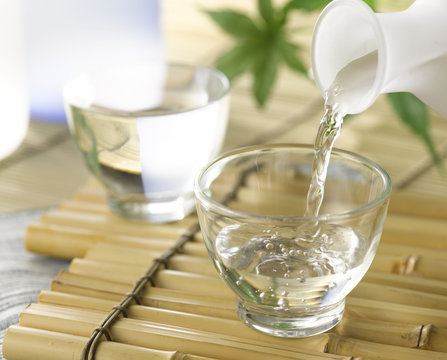 A cup of Japanese sake pouring from the sake decanter