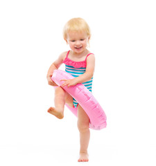 Baby girl in swimsuit playing with inflatable ring