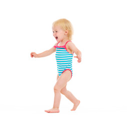 Happy baby in swimsuit running on white