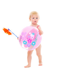 Baby girl in swimsuit holding pinwheel and beach ball