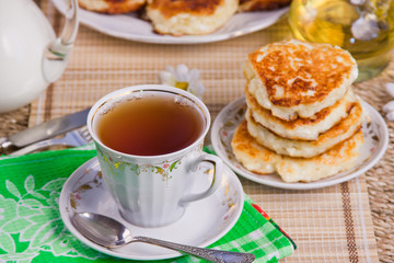 cup with tea, curd pancakes on a dish and milk