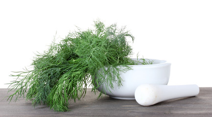 Dill in a mortar and pestle on wooden